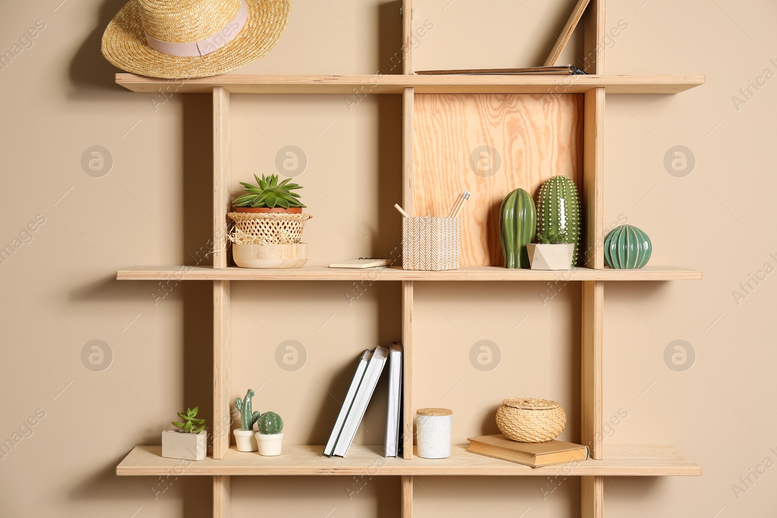 Photo of Wooden shelves with different decorative elements on beige wall