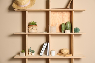 Photo of Wooden shelves with different decorative elements on beige wall