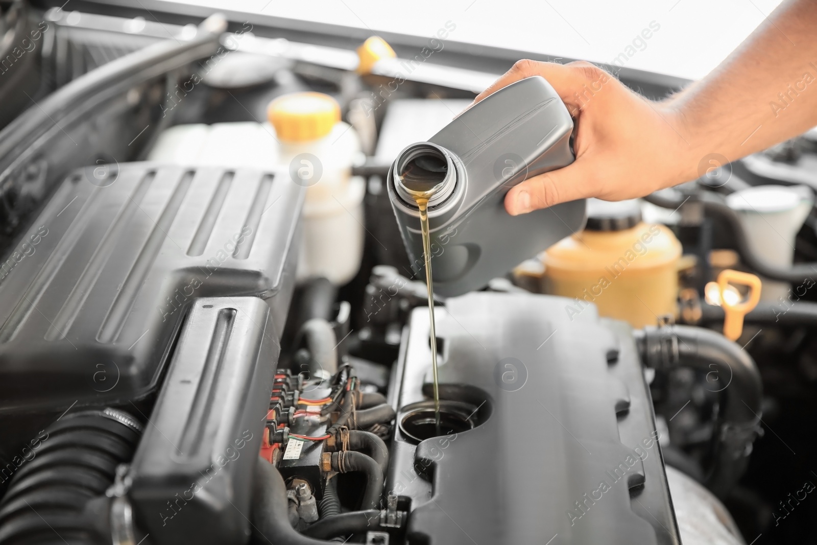 Photo of Mechanic pouring oil into car engine, closeup