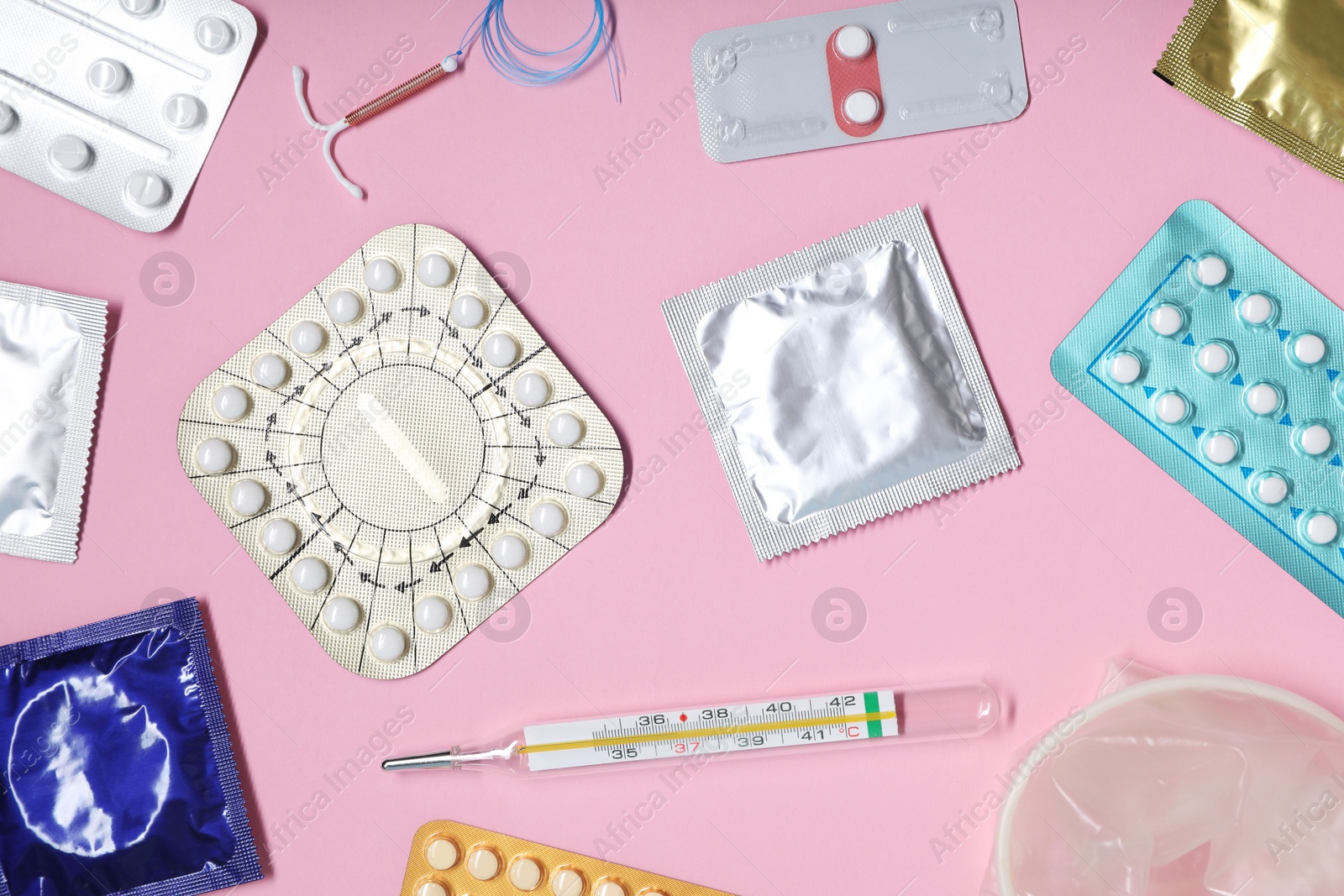 Photo of Contraceptive pills, condoms, intrauterine device and thermometer on pink background, flat lay. Different birth control methods