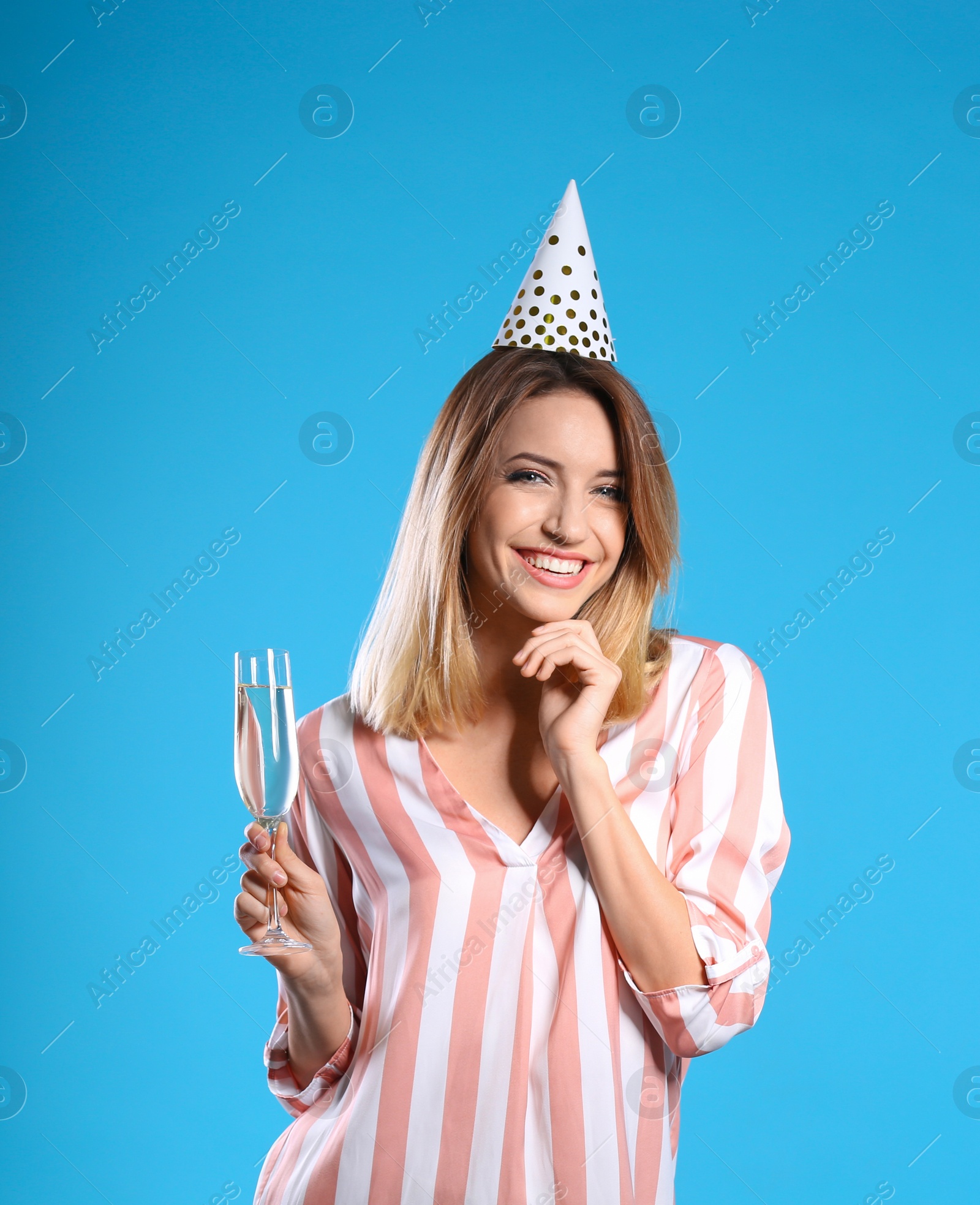 Photo of Portrait of happy woman with party hat and champagne in glass on color background