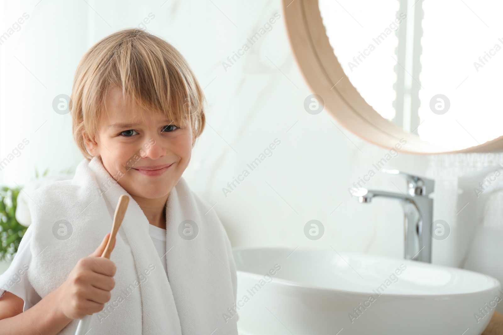 Photo of Cute little boy brushing teeth in bathroom. Space for text