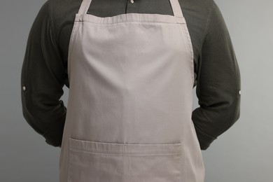 Man in kitchen apron on grey background, closeup. Mockup for design