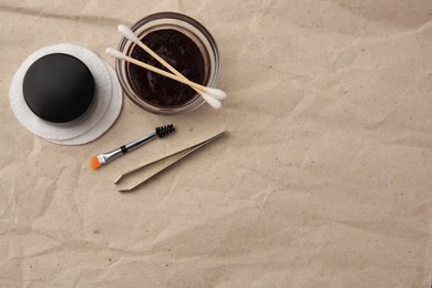 Photo of Flat lay composition with eyebrow henna and tools on crumpled paper. Space for text