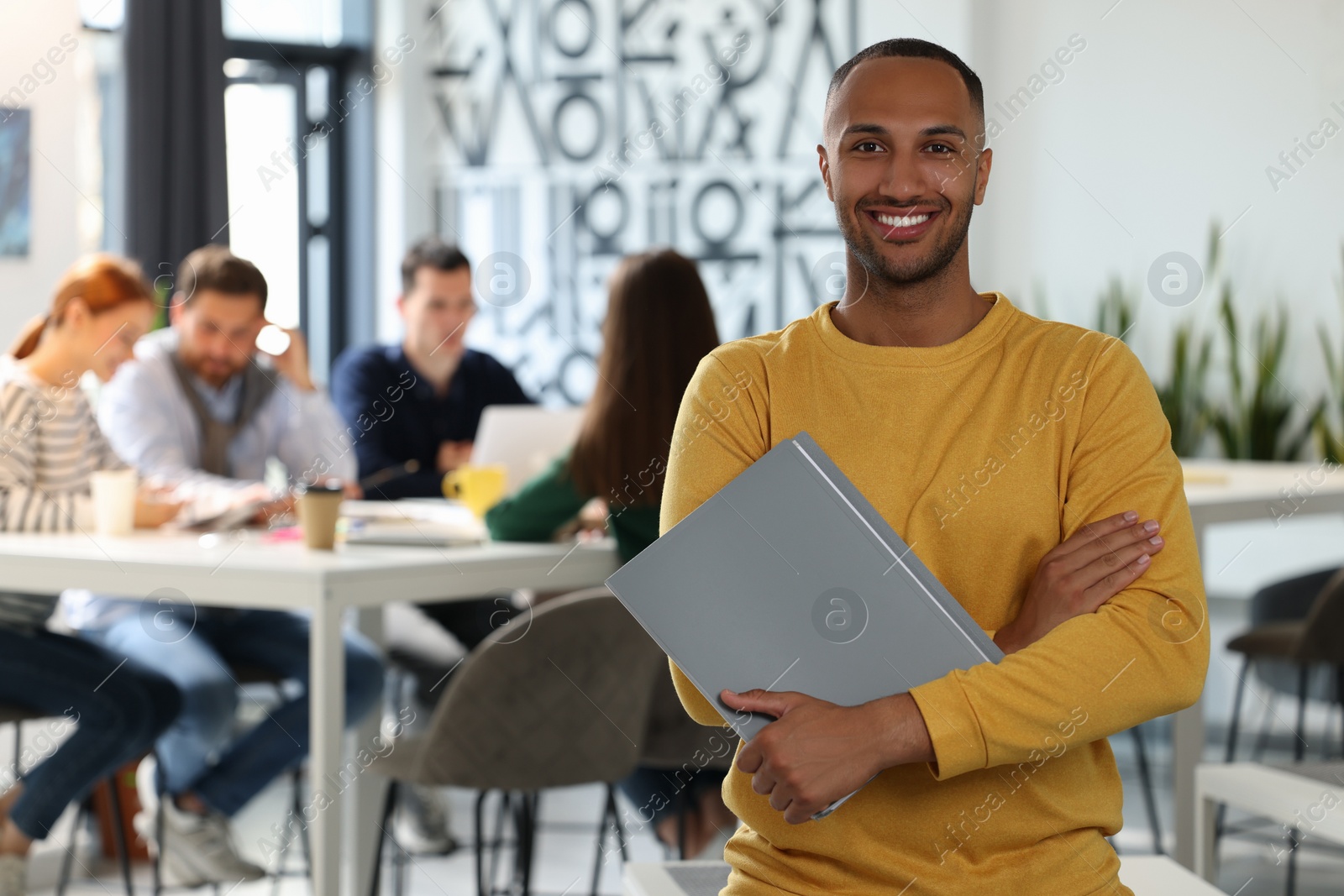 Photo of Team of employees working together in office. Happy man with folder indoors, space for text