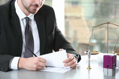 Photo of Male notary working with documents at table in office, closeup