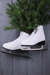 Photo of Pair of ice skates with fir branches hanging on grey wooden wall