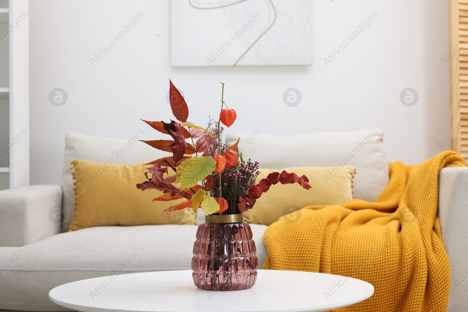 Photo of Vase with bouquet on side table and comfortable sofa in living room
