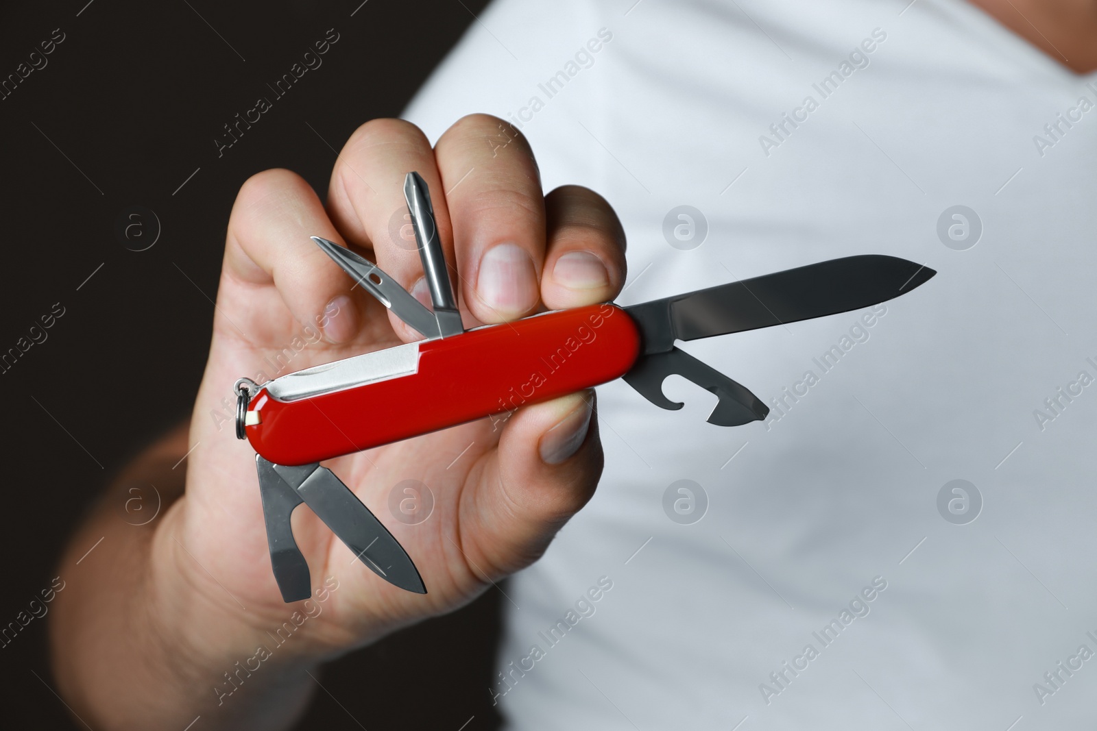 Photo of Man holding multitool on dark background, closeup