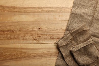 Photo of Burlap fabric on wooden table, top view. Space for text