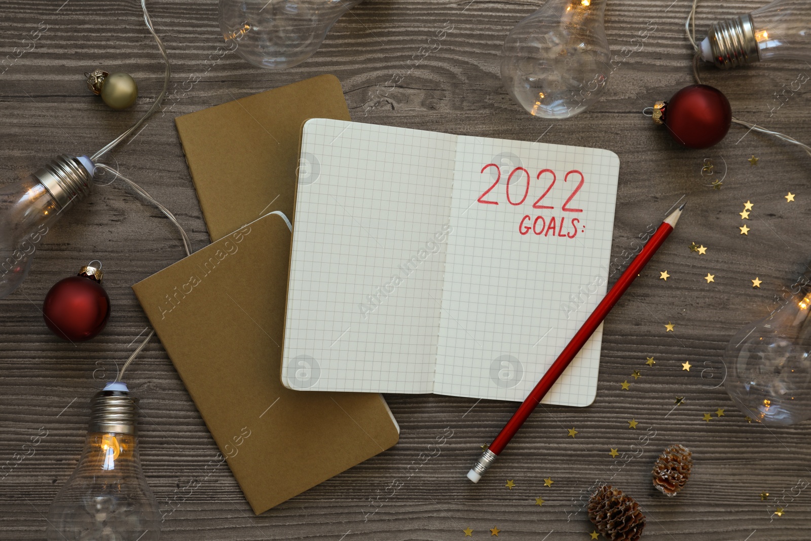 Photo of Inscription 2022 Goals written in planner and Christmas decor on wooden background, flat lay. New Year aims