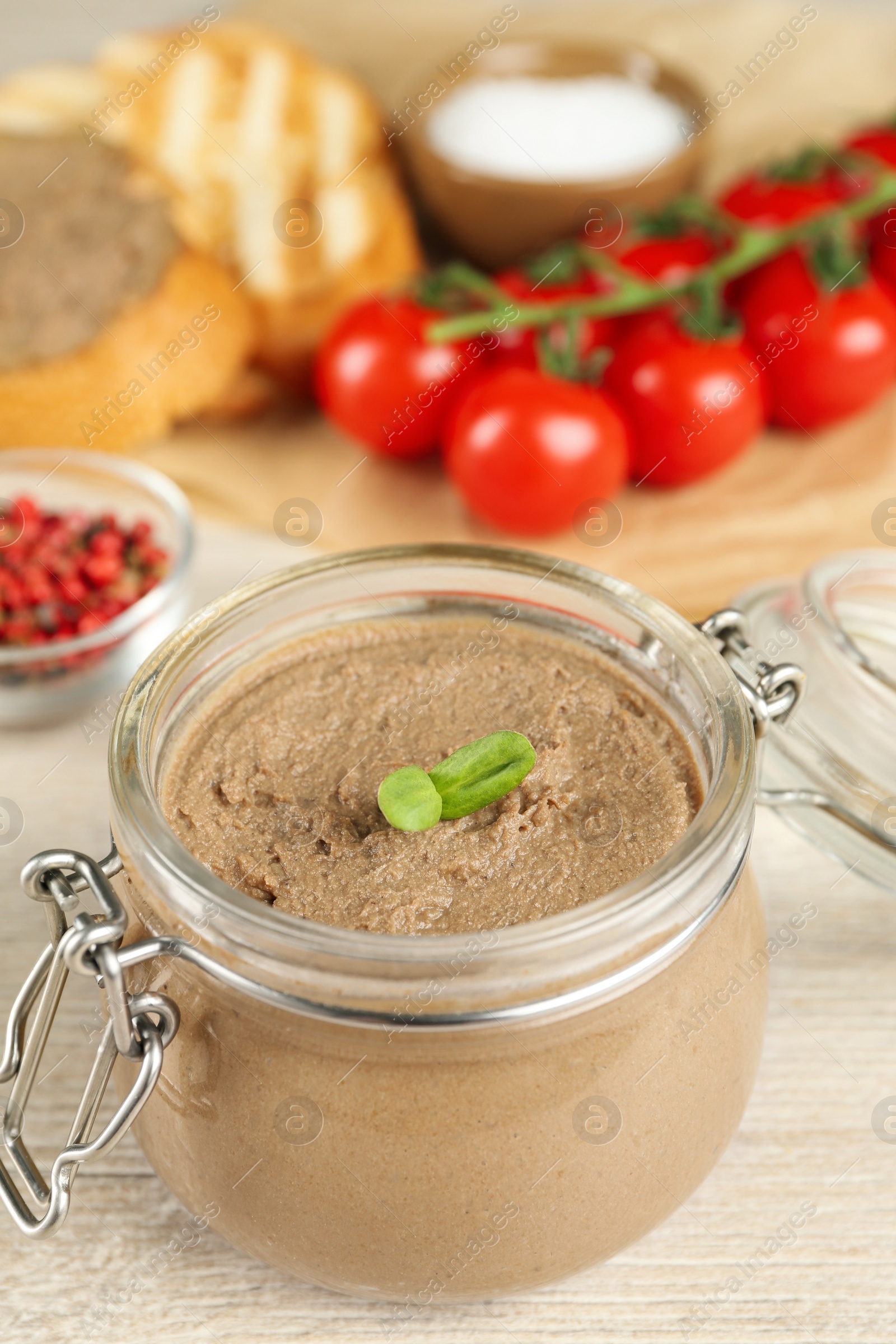 Photo of Glass jar with delicious liver pate on white wooden table, closeup