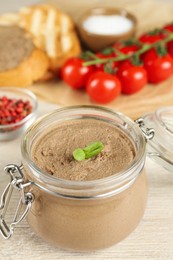 Photo of Glass jar with delicious liver pate on white wooden table, closeup