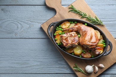 Photo of Tasty cooked rabbit with vegetables in baking dish on grey wooden table, top view. Space for text
