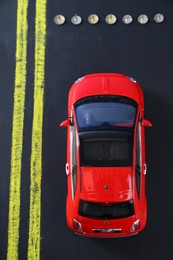 Photo of Development through barriers overcoming. Red toy car movement blocked by pins on road, top view