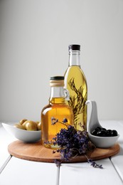 Different cooking oils and ingredients on white wooden table against light background