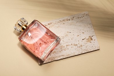 Photo of Luxury women's perfume in bottle on beige background, top view