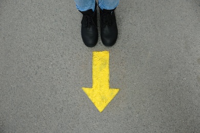 Photo of Person standing near arrow on asphalt, top view