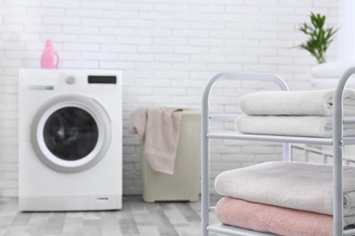 Photo of Folded clean terry towels on shelving unit in laundry room, space for text