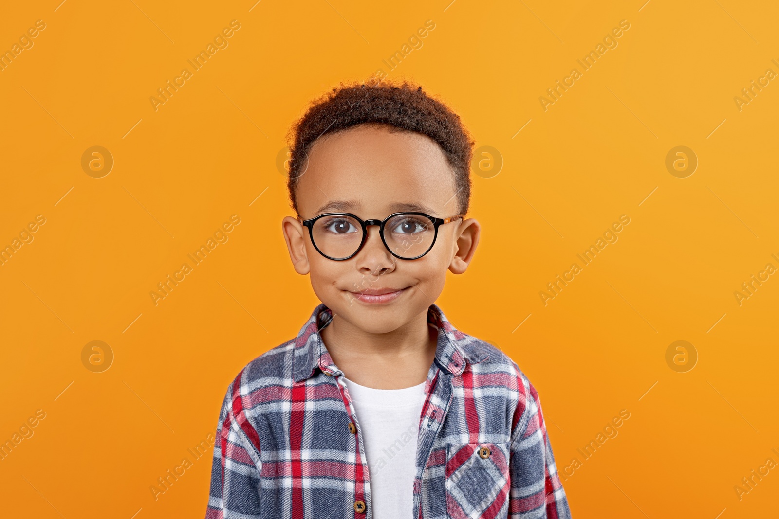 Photo of Cute African-American boy with glasses on orange background