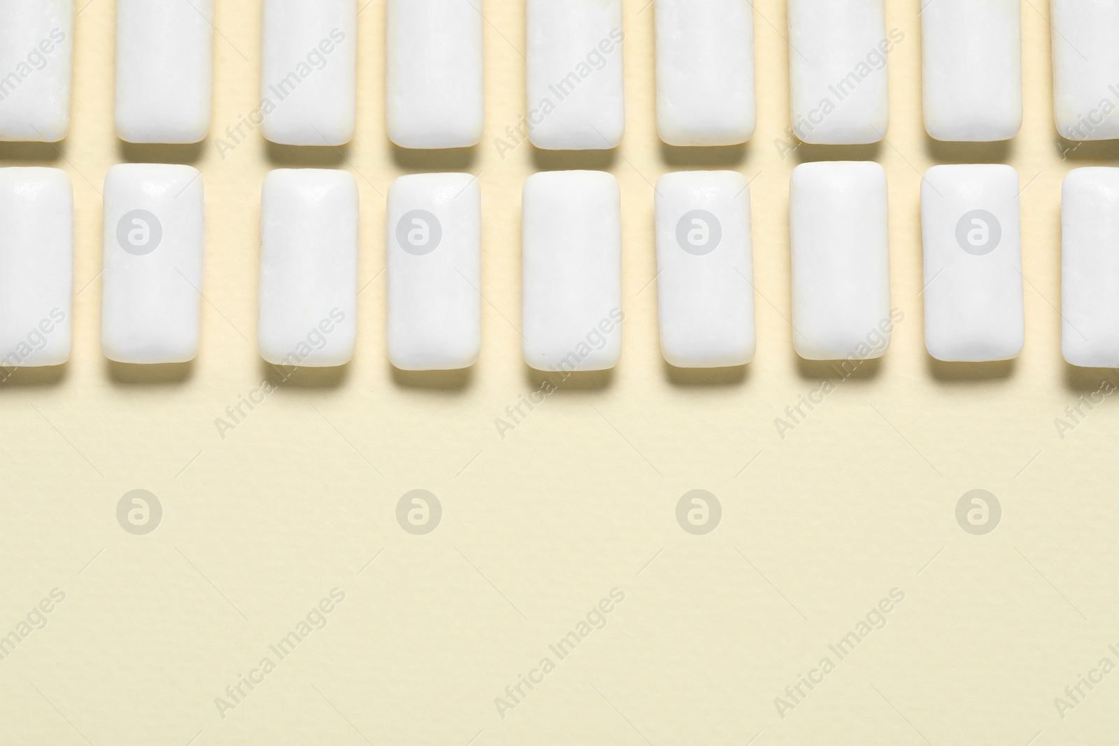 Photo of Tasty white chewing gums on beige background, flat lay. Space for text