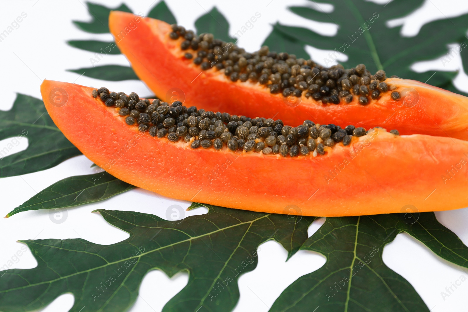 Photo of Fresh ripe papaya slices and leaf on white background, closeup