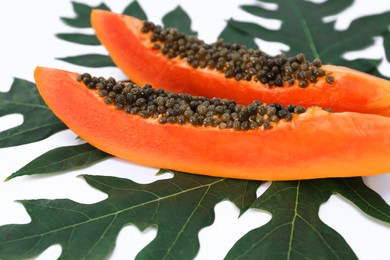 Fresh ripe papaya slices and leaf on white background, closeup