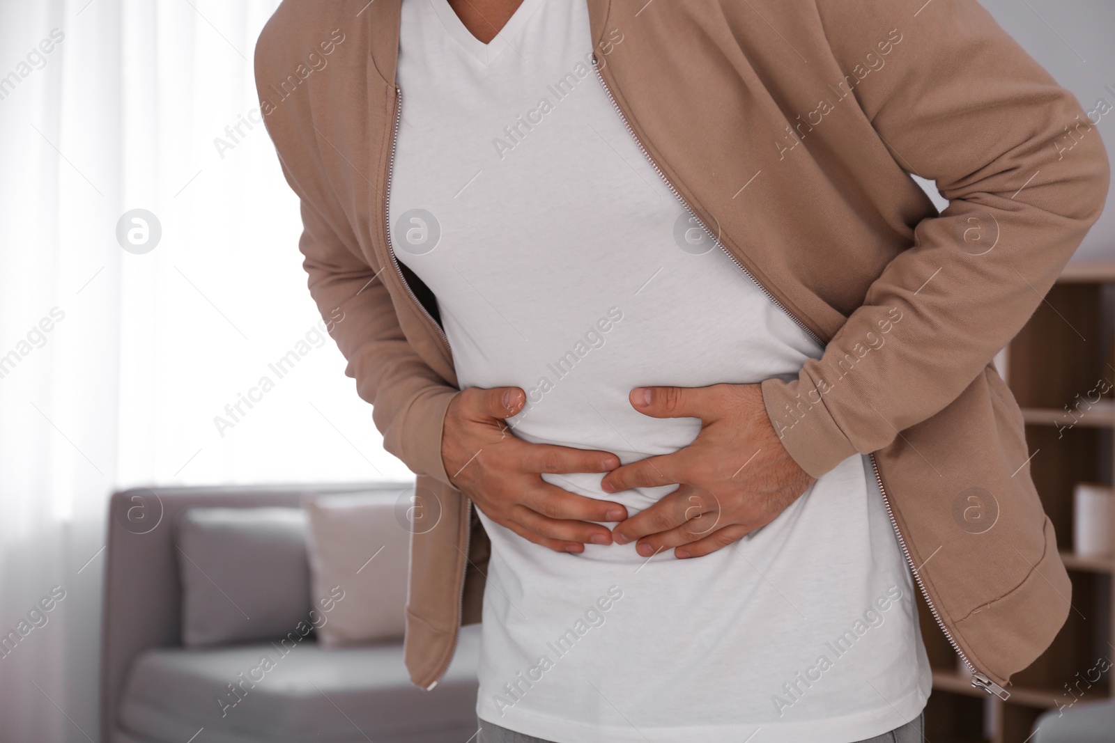 Photo of Man suffering from stomach ache at home, closeup. Food poisoning