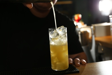 Photo of Bartender making delicious cocktail with vodka at wooden counter in bar, closeup
