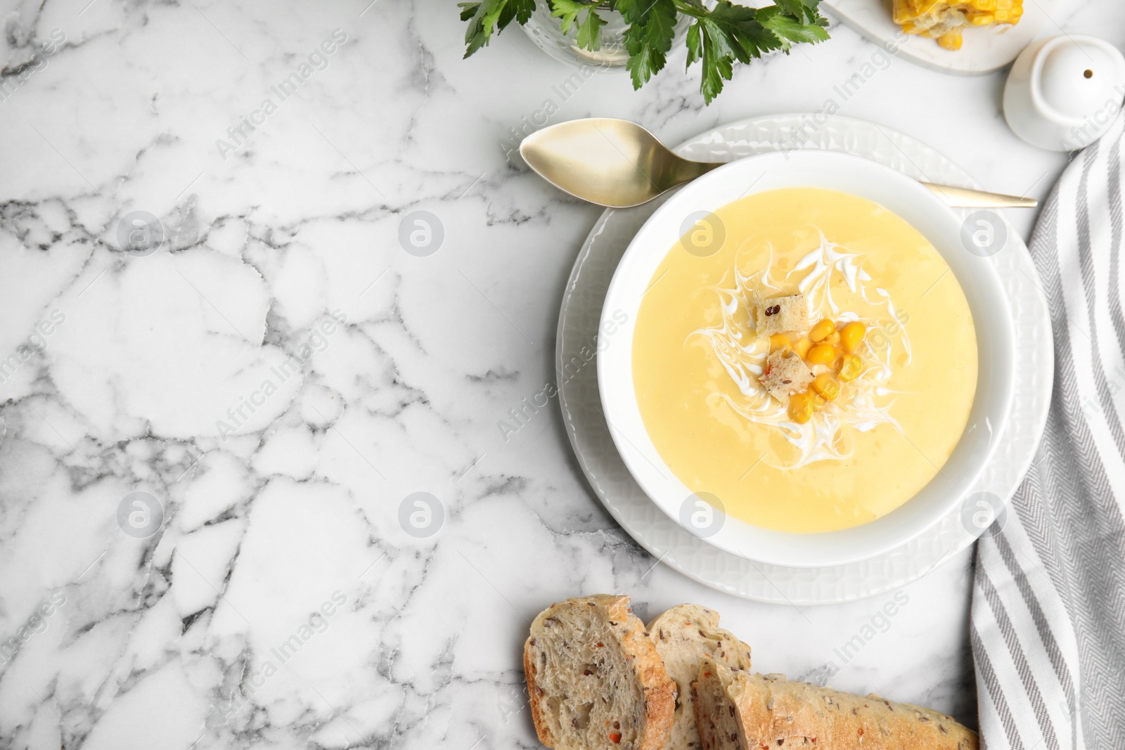 Photo of Delicious corn cream soup served on white marble table, flat lay. Space for text