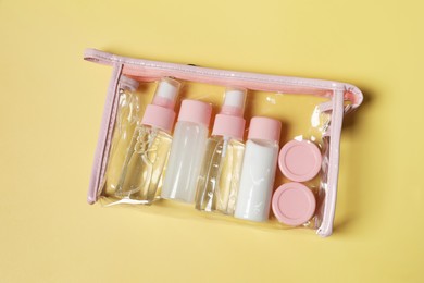 Photo of Cosmetic travel kit in plastic bag on yellow background, top view