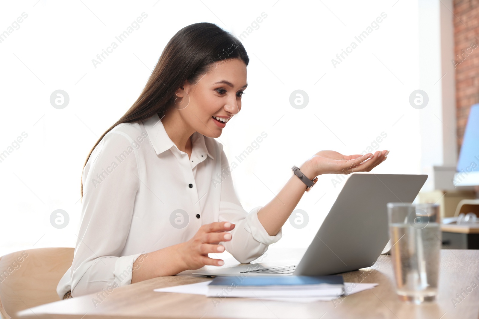 Photo of Young woman using video chat on laptop in home office