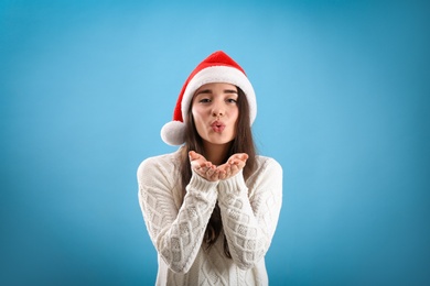 Beautiful woman wearing Santa Claus hat on light blue background