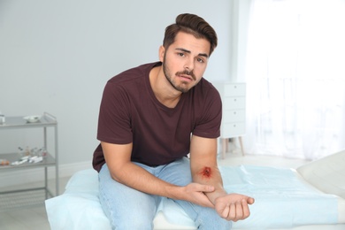 Young man with injured arm in clinic. First aid