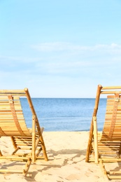 Sandy beach with empty wooden sunbeds on sunny day