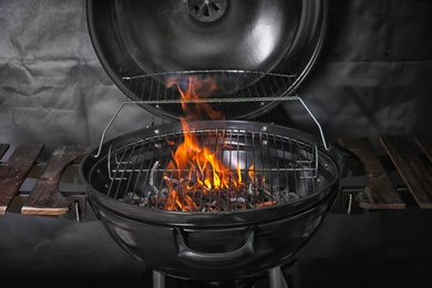 Photo of New modern barbecue grill with coals on black background