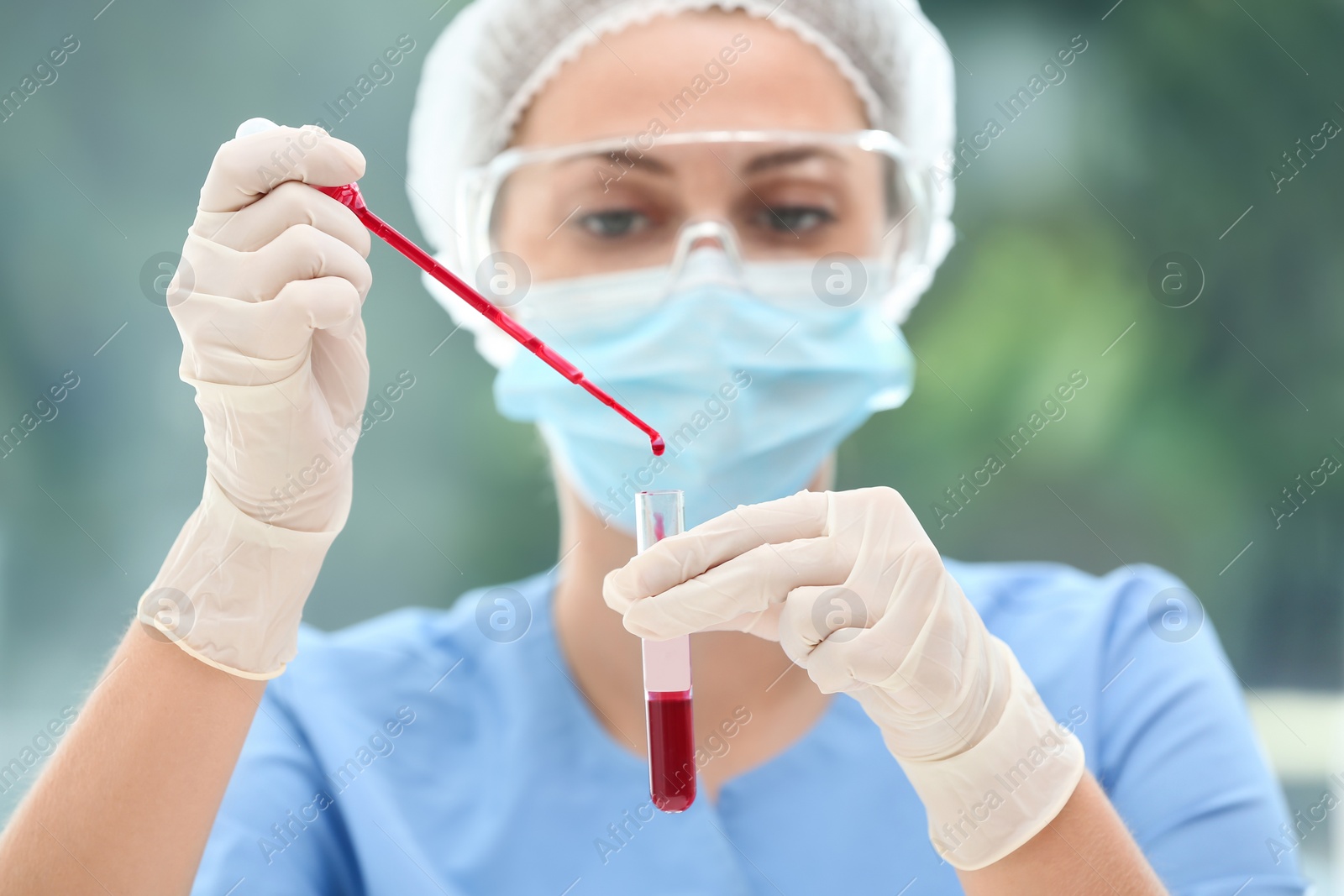 Photo of Scientist dripping blood into test tube in laboratory