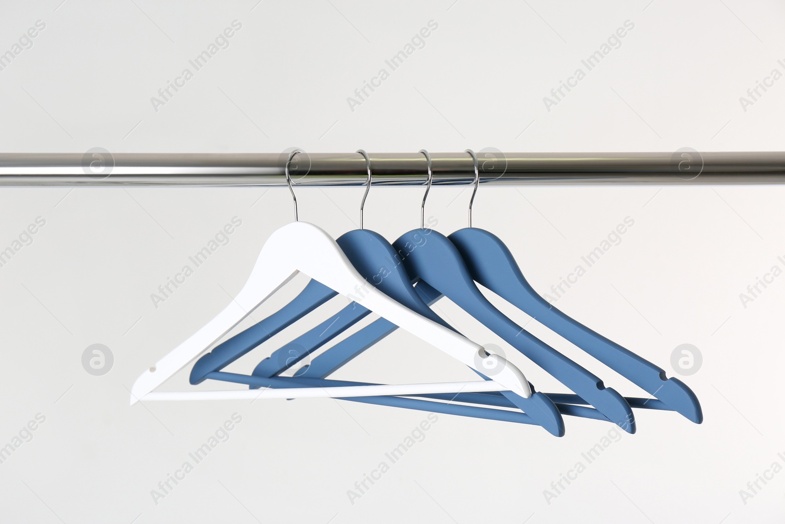 Photo of Metal rack with clothes hangers on white background