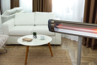 Modern electric infrared heater in room. Space for text