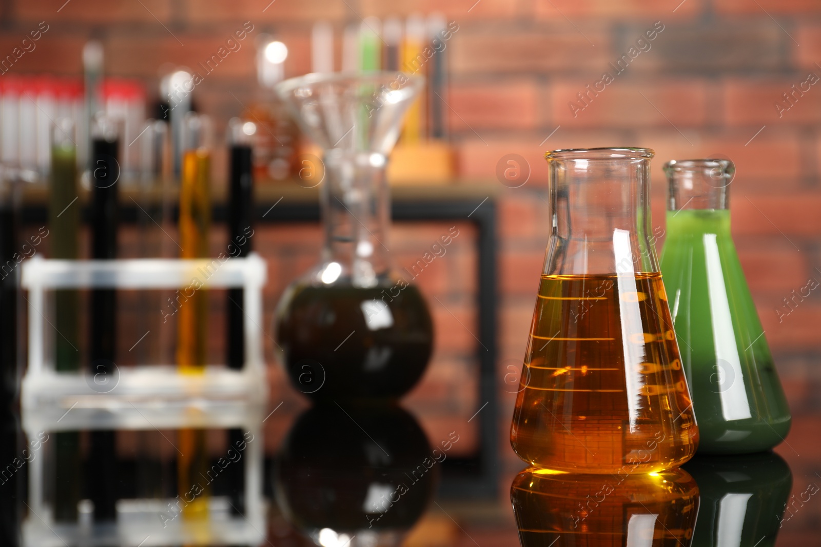 Photo of Laboratory glassware with different types of oil on mirror table indoors, closeup