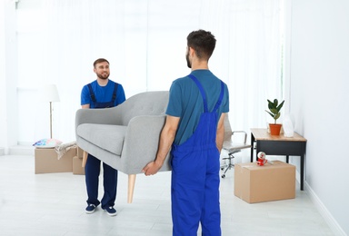 Photo of Young workers carrying sofa in room. Moving service
