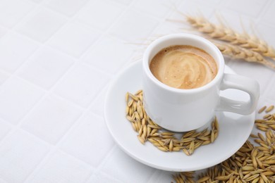 Cup of barley coffee, grains and spikes on white table, closeup. Space for text