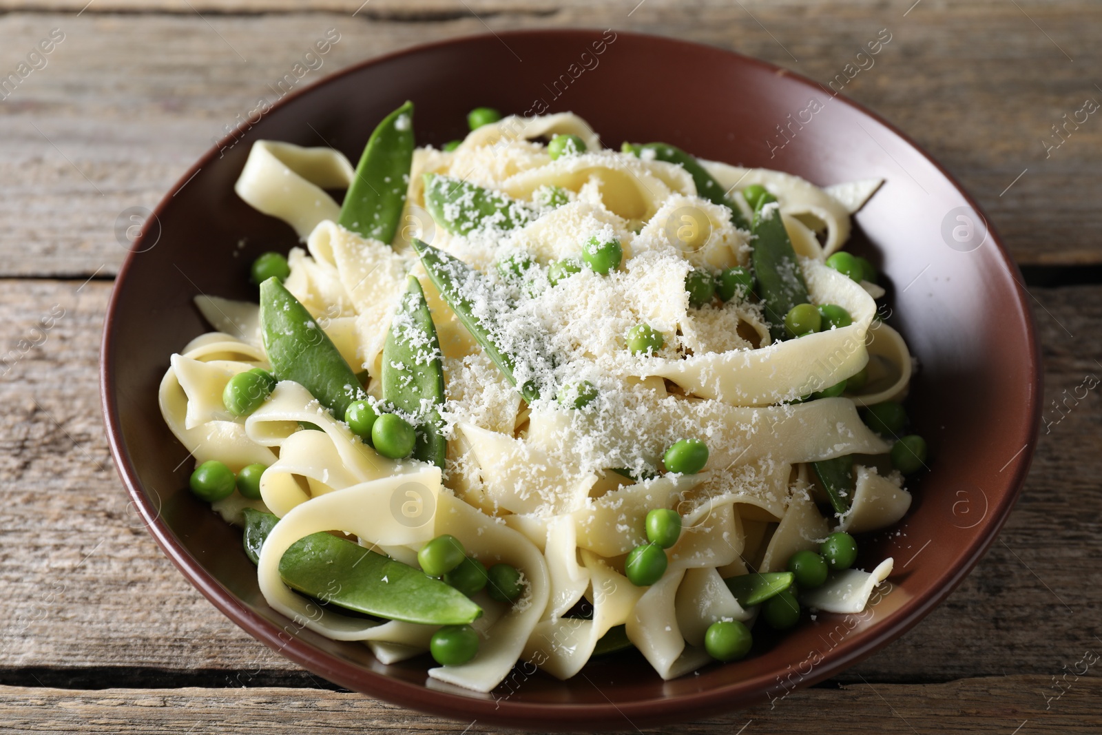 Photo of Delicious pasta with green peas and cheese on wooden table