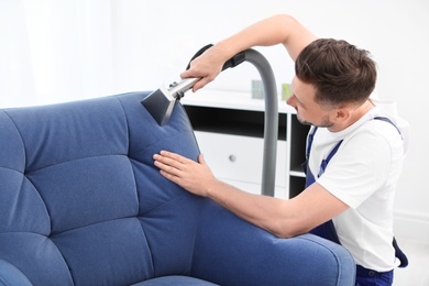 Dry cleaning worker removing dirt from armchair indoors