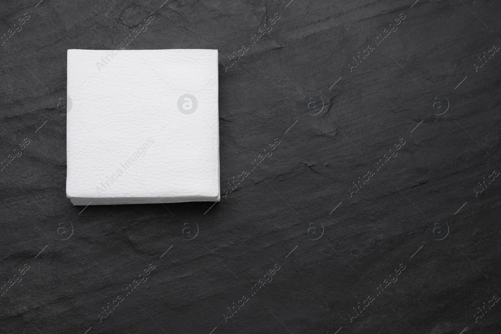 Photo of Stack of paper tissues on black table, top view. Space for text