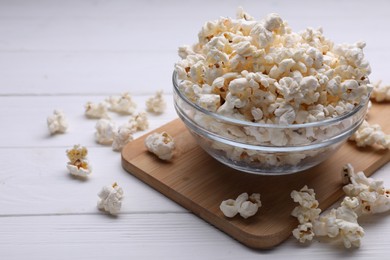 Photo of Tasty popcorn in bowl on white wooden table