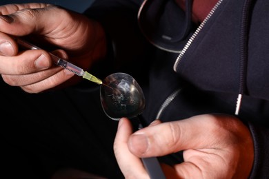 Photo of Addicted man filling syringe with drug, closeup