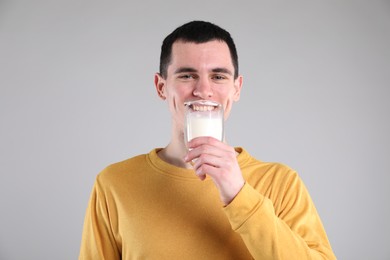 Milk mustache left after dairy product. Man drinking milk on gray background