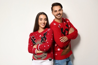 Photo of Young couple in Christmas sweaters on white background