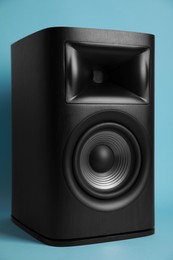 Photo of One wooden sound speaker on light blue background
